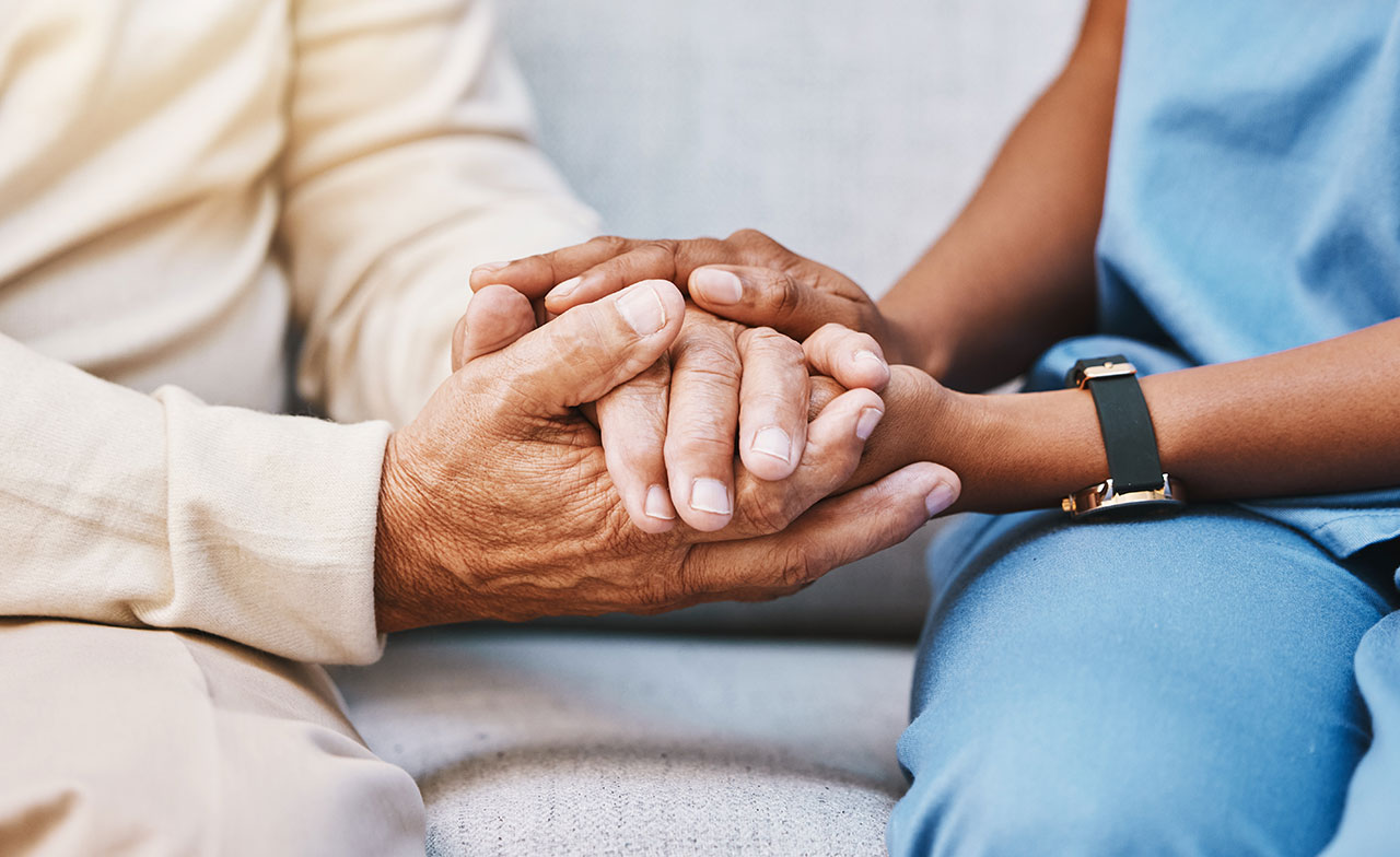 Krankenschwester hält die Hände einer älteren Patentin