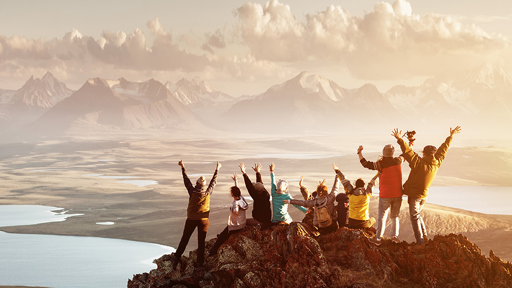 En grupp hikers står på ett berg och sträcker händerna upp i luften