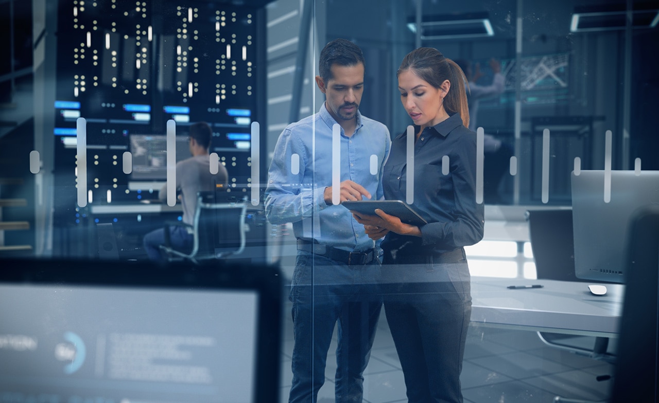 To personer ser på nettbrett i datasenter omgitt av skjermer og servere. To personer ser på nettbrett i datasenter omgitt av skjermer og servere.