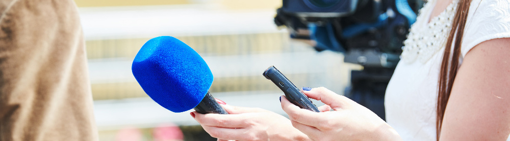 Journalistin interviewt eine Person mit blauem Mikrofon