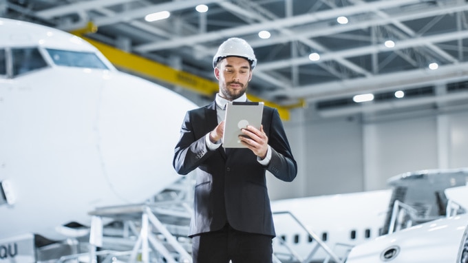 a man in a airplane hanger looking at a tablet