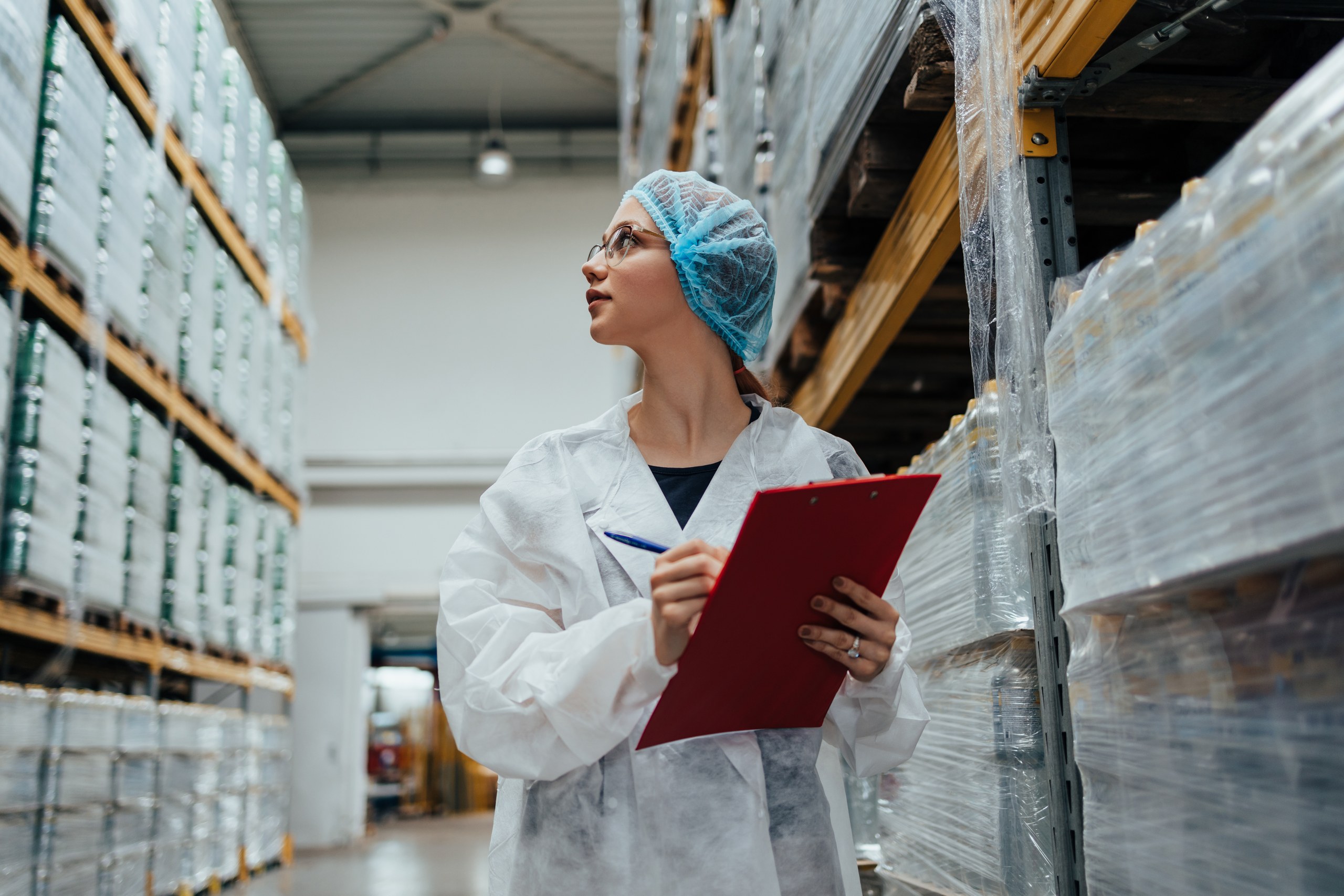 Life sciences worker in protective clothing checking inventory in a pharmaceutical warehouse