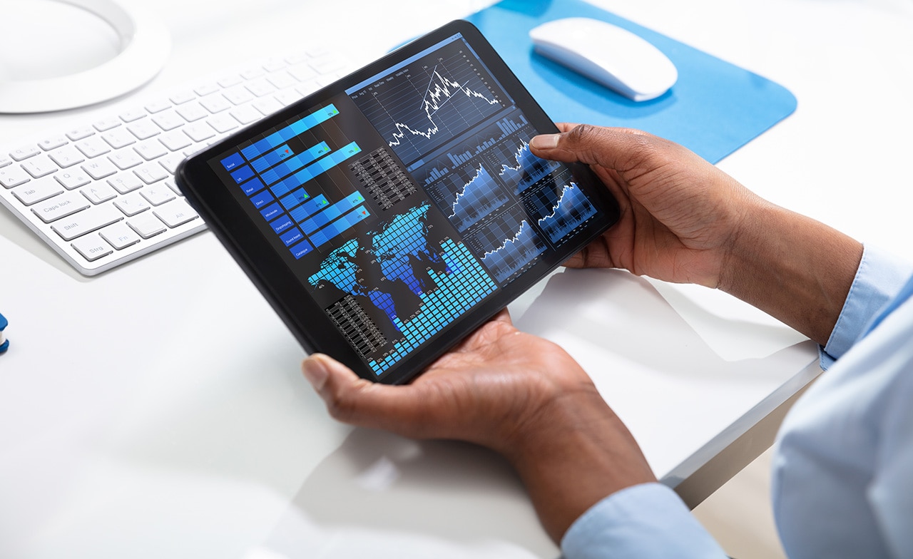 To personer ser på grafer på en laptop ved møtebord.