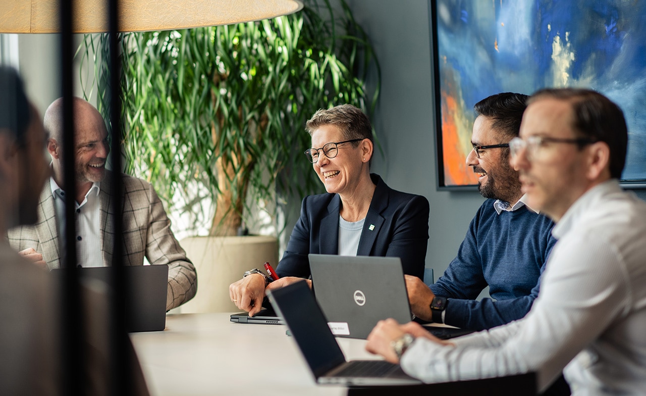To personer ser på grafer på en laptop ved møtebord.