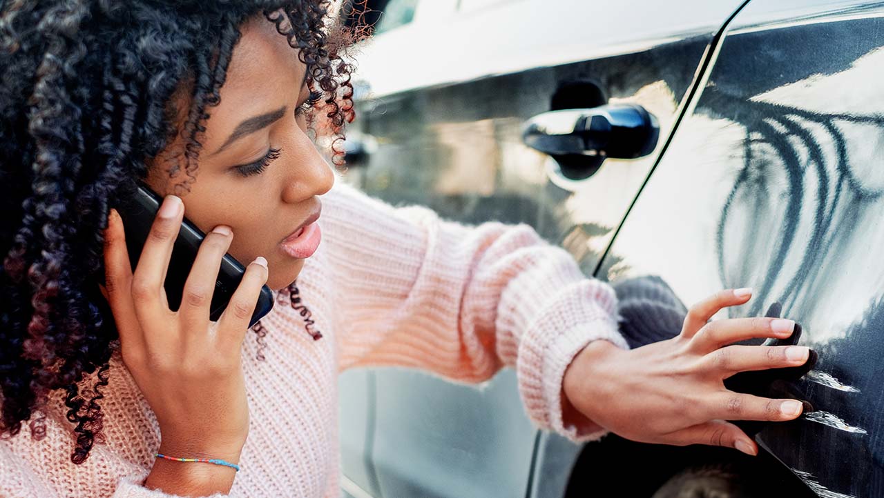 Le propriétaire de la voiture parle à un représentant d’assurance sur un appareil mobile pour expliquer les dommages causés à la voiture après un accident