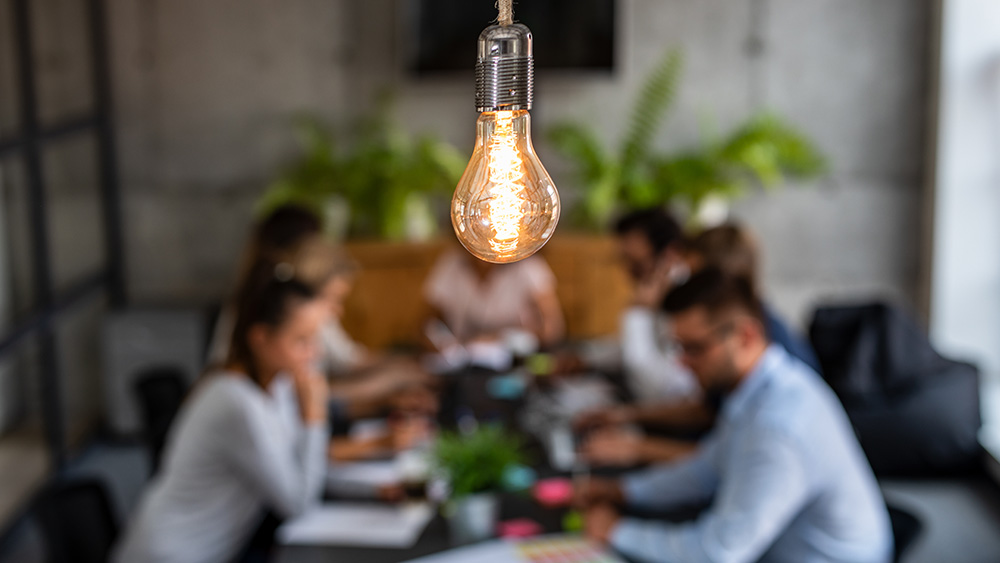 Group of professionals in a meeting with a lightbulb in the foreground 