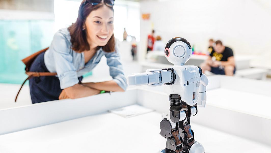 Lady smiling whilst examining robot