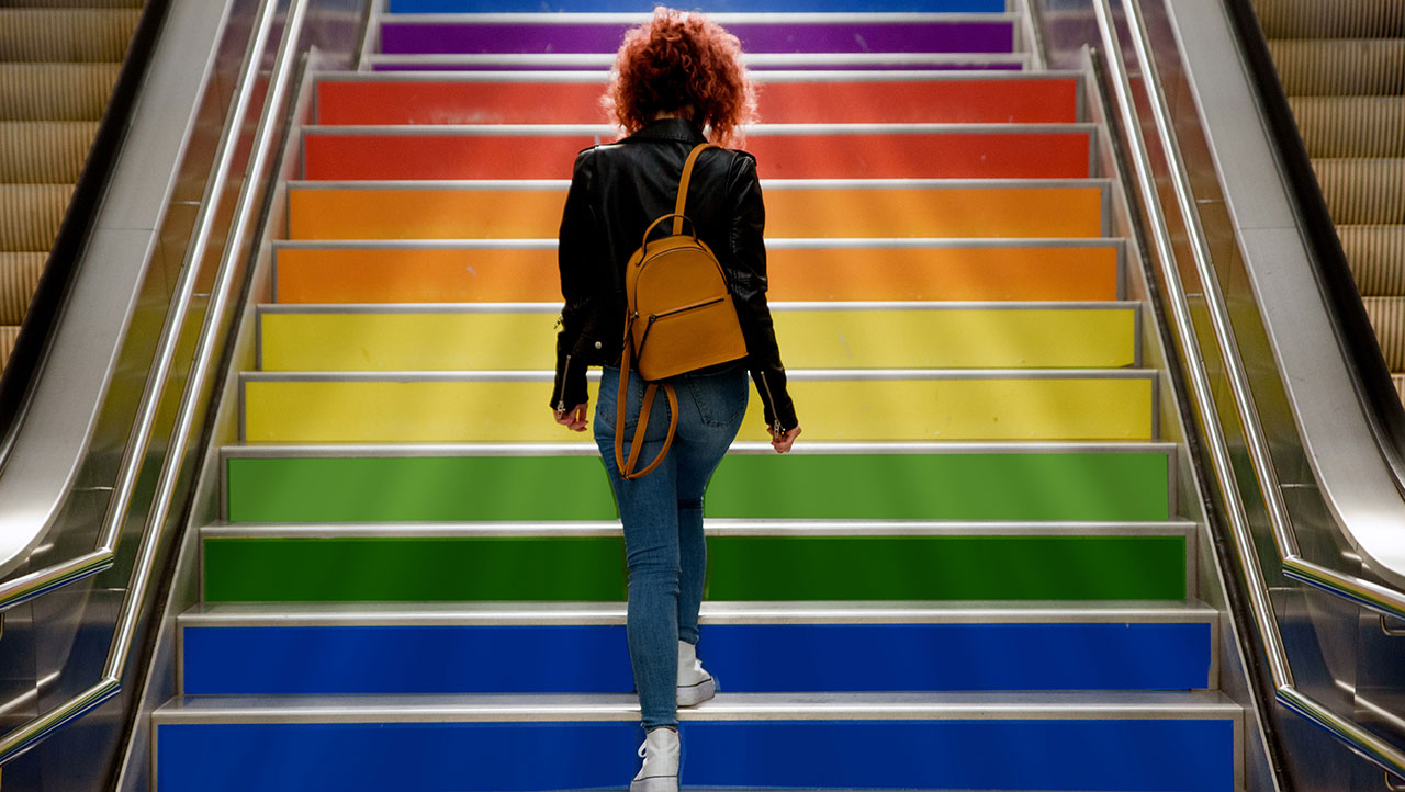 A person walking up rainbow colored steps