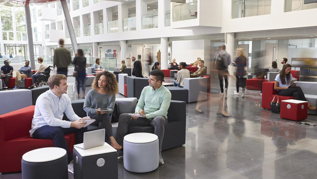 University students sit and chat in a university campus building common area