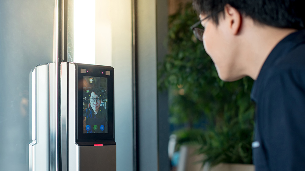 Asian man using face scanner to unlock glass door