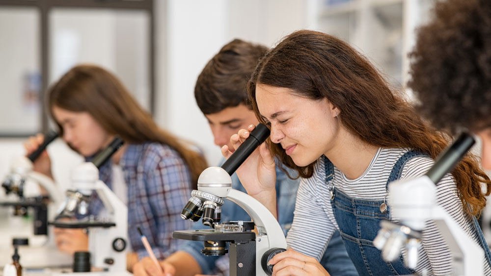 Group of school children looking into microscopes during science lesson