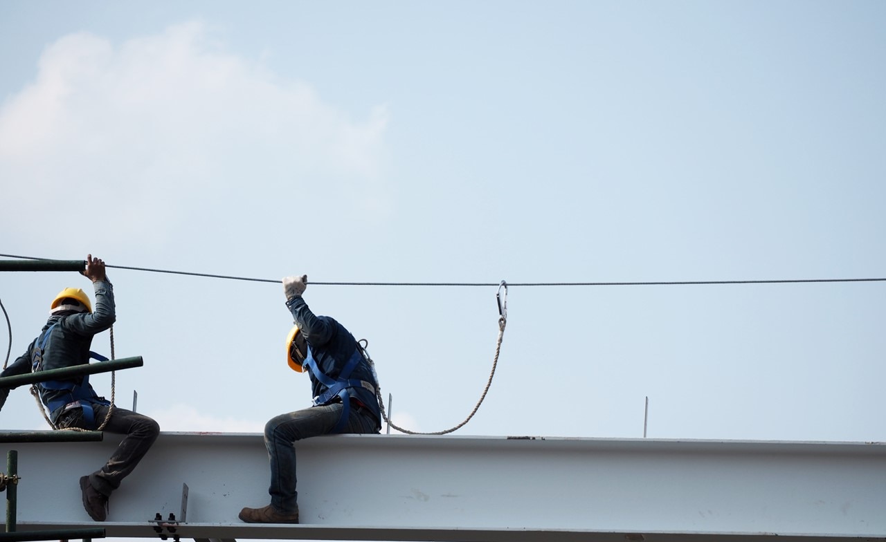 Men with safety harness working on a high beam construction