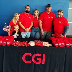 Team posing for a photo behind a CGI branded table with branded giveaways