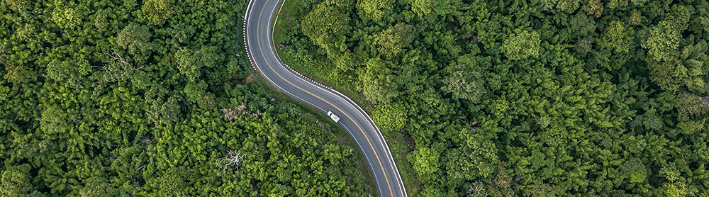 Aerial view of a road weaving through forest surroundings