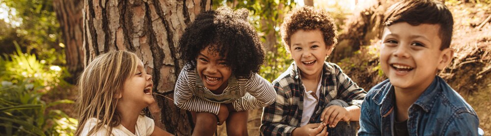 four children smiling in the woods