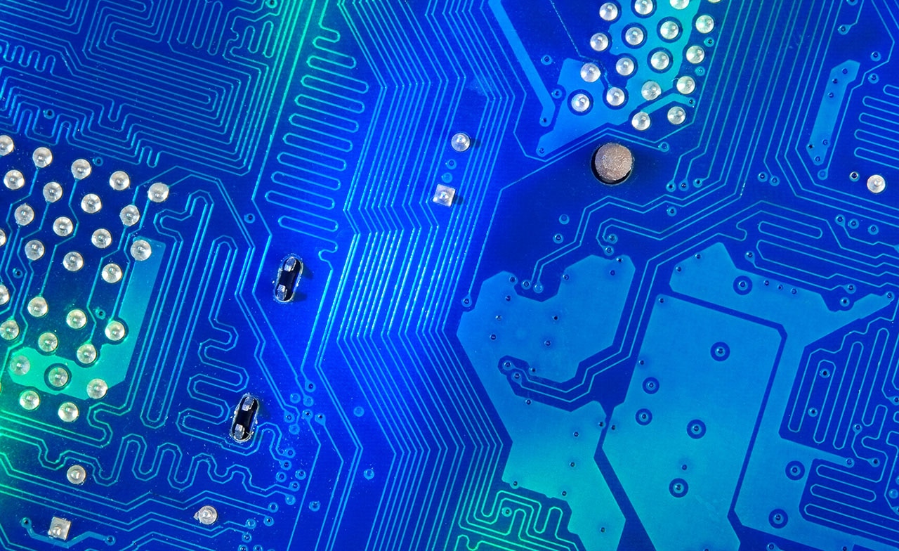 Nærbilde av blått kretskort med ledningsbaner og komponenter.