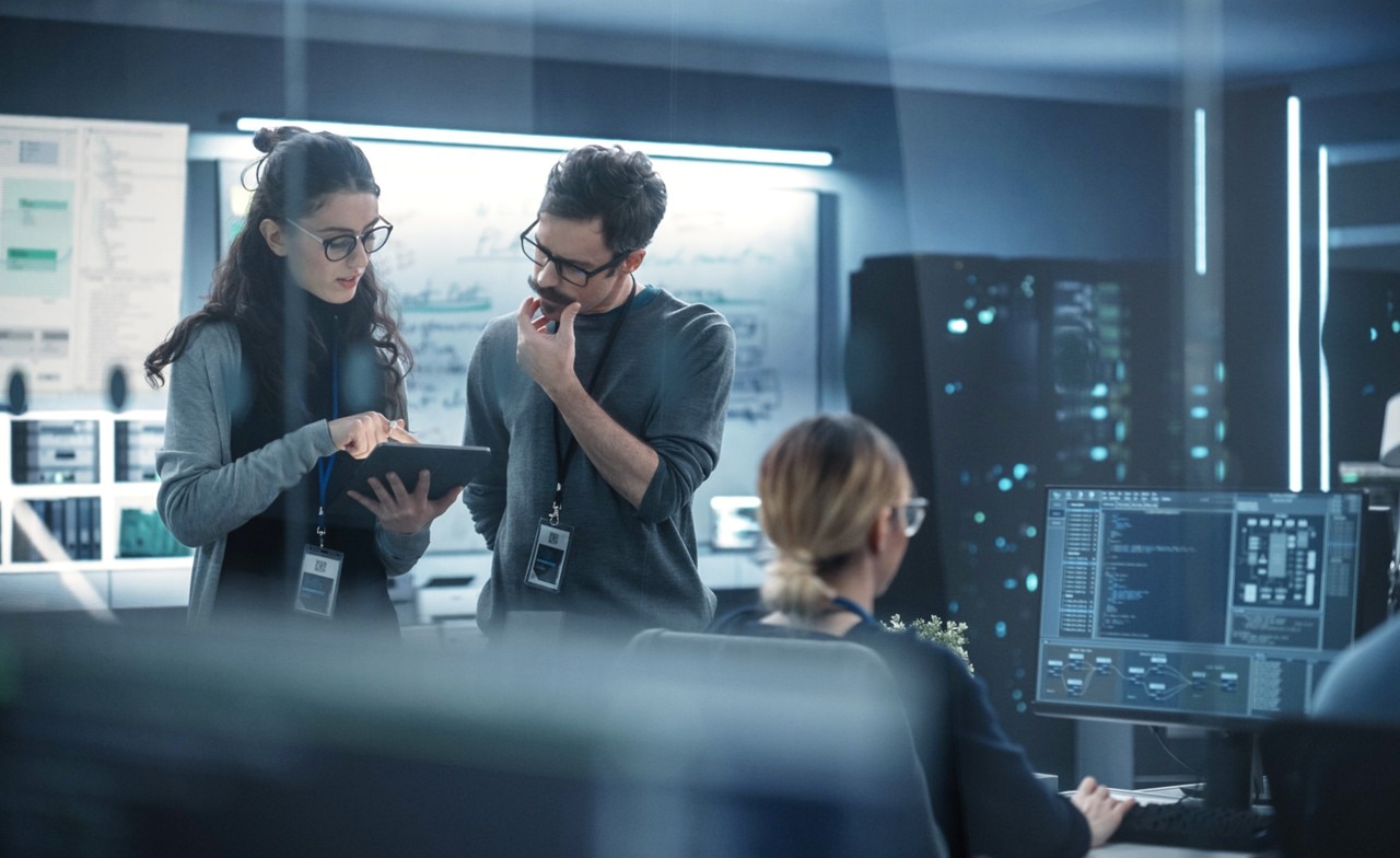 People standing looking at a laptop in a computer room