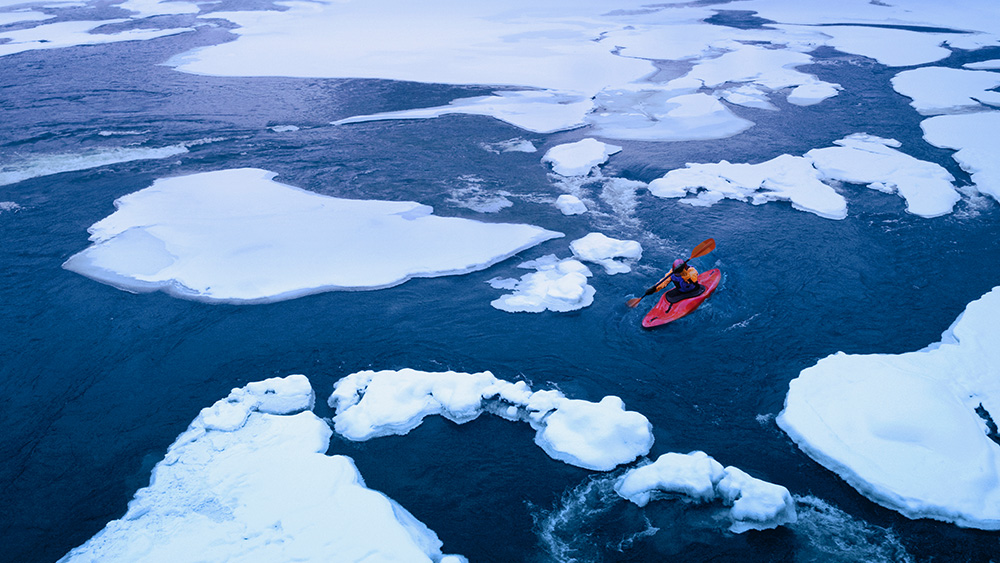 person kayaking in ice water 