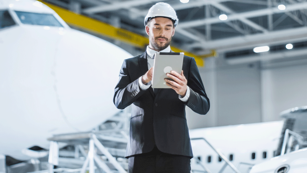Person using tablet device stands in front of aircraft