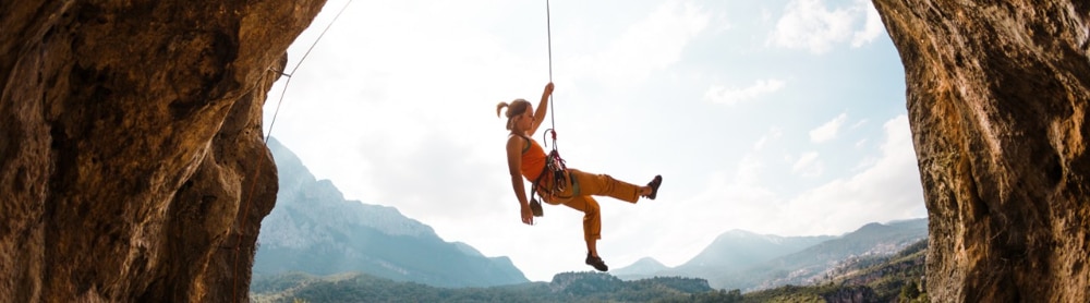 Eine Bergsteigerin an einem Seil hängend