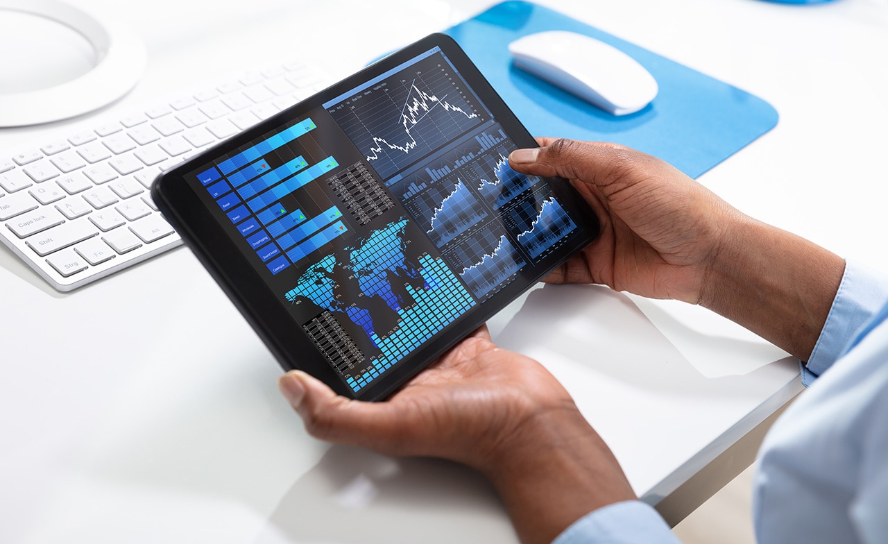 Person holder nettbrett med visning av grafer, kart og datavisualisering.