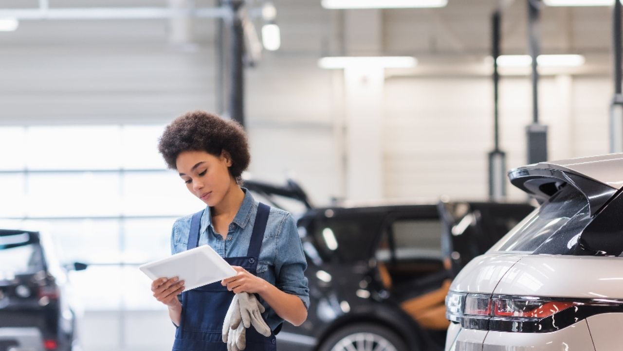 Frau steht mit einem Tablet in einem Autohaus