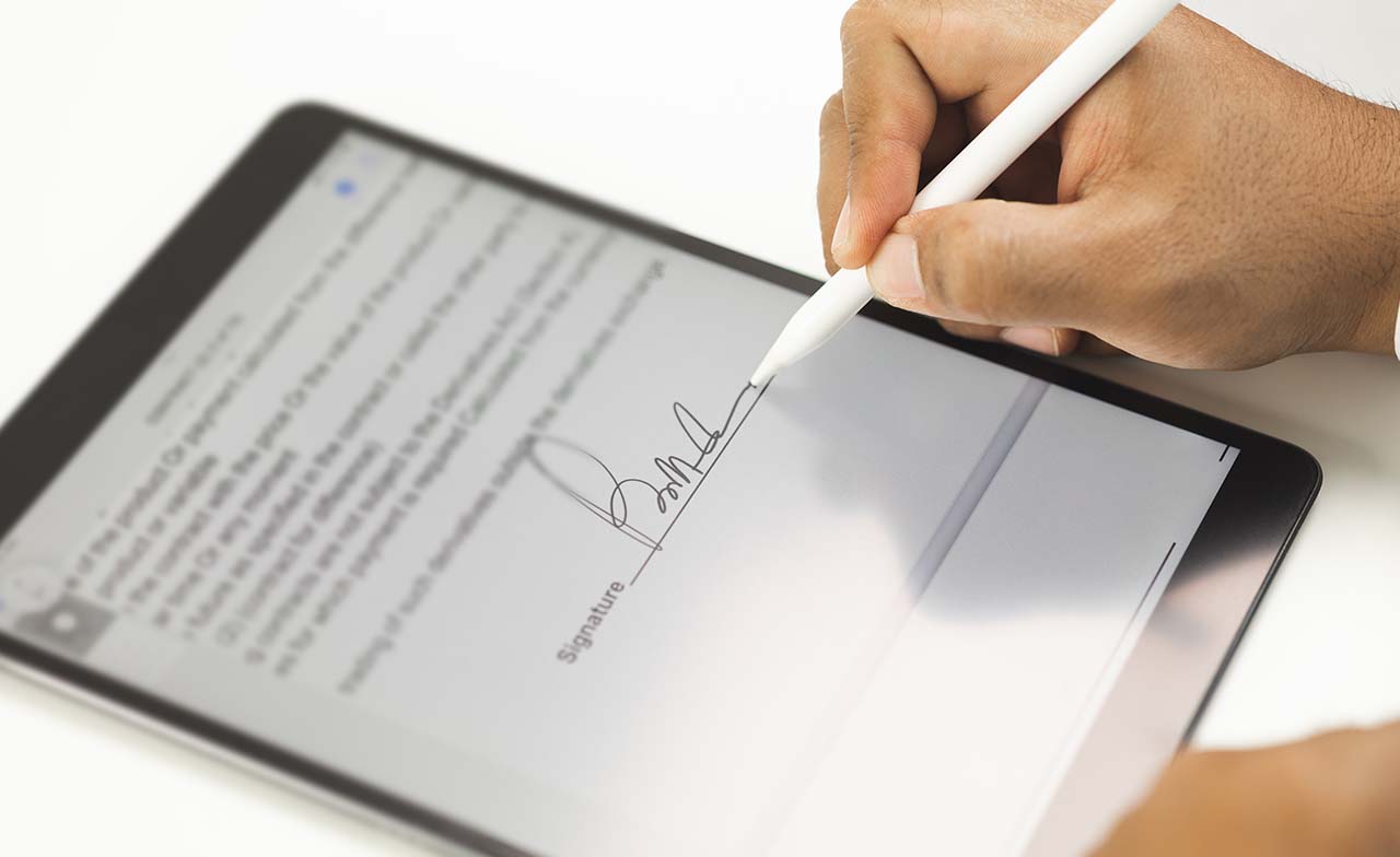 Hand signing a digital document on a tablet