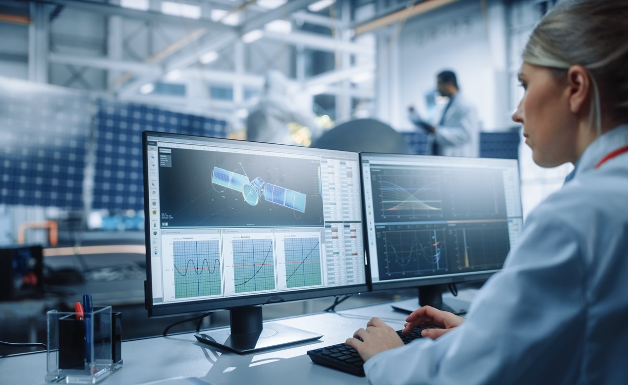 Female space technician working on computer looking at satellite data