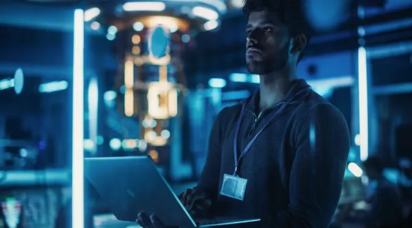 AI consultant standing with a laptop working in a dimly lit server room