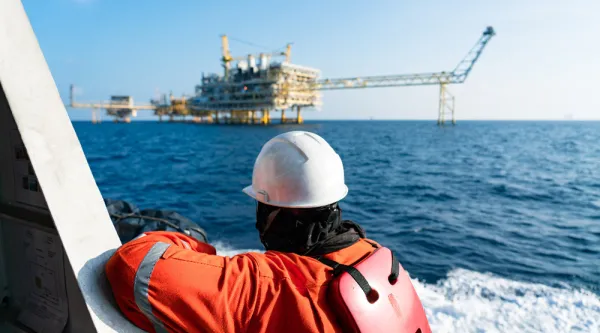 operational worker on the sea looking at an oil rig