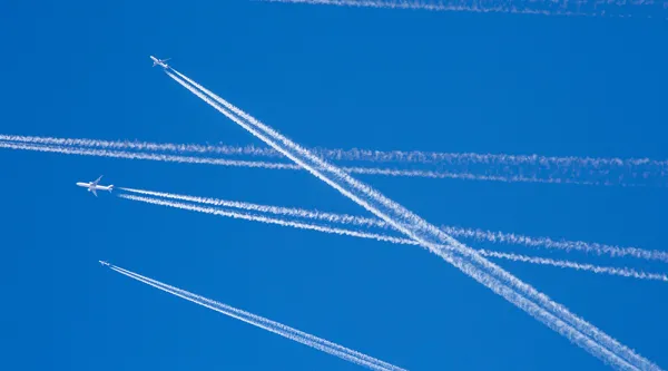 Several civilian or military aircraft safely flying at high altitude showing vapour trails