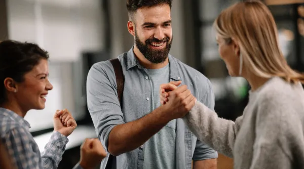 Trois professionnels souriants célèbrent une réussite en équipe