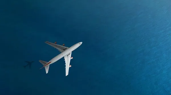 Commercial aircraft in flight over water 