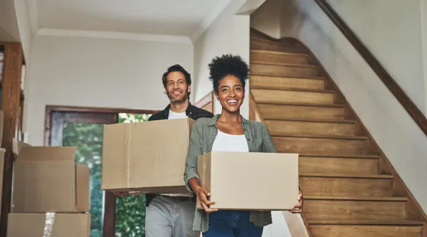 Couple carrying moving boxes into new home