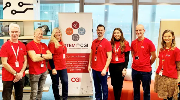 CGI Volunteers standing in front of a STEM Camp banner