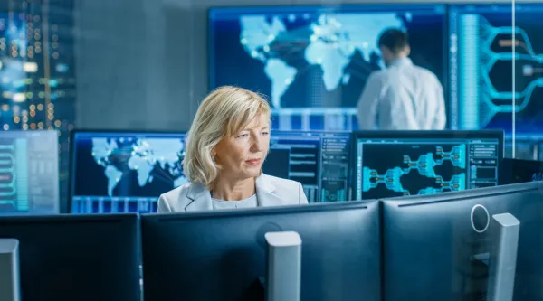 female cybersecurity analyst monitoring screens at a security operations center