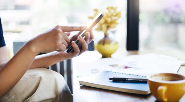 Person sitting at table, holding mobile phone
