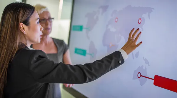 businesswoman showing global delivery network map on large screen