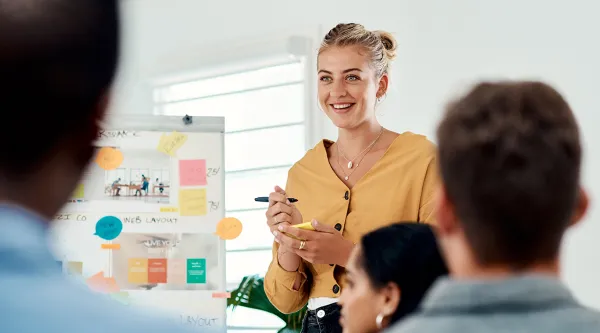 Kvinna leder workshop med postit lapp och penna i handen
