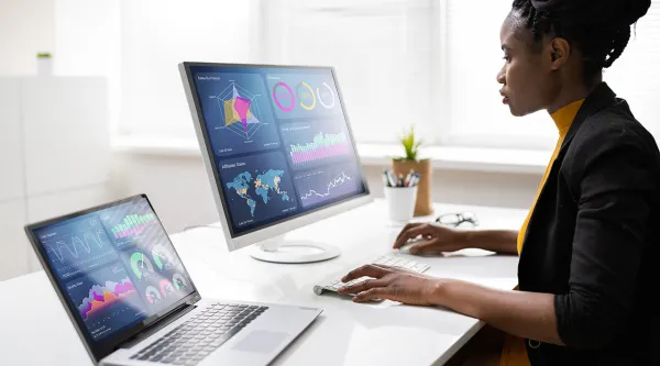 AI consultant looks at data charts on two screens