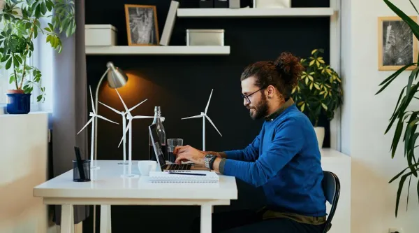man working from home at desk with models of wind turbines