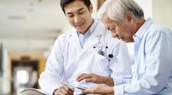 Medical professional looking at tab with elder patient