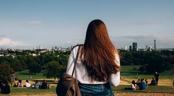 Female in a park looking out to a city skyline 