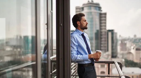 Person in business attire standing on a balcony overlooking the city