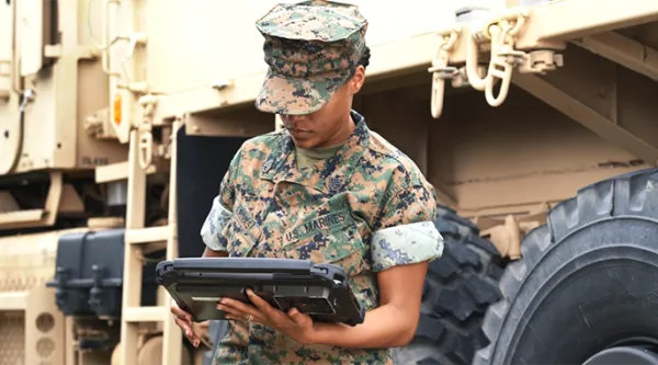 servicemember looking at tablet in front on vehicle
