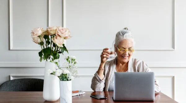 Person sitting at desk with flowers looking at laptop