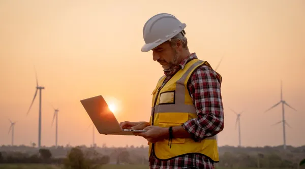an engineer using a laptop in a wind farm