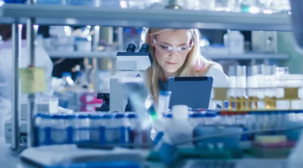 A scientist seating in a lab working with a microscope