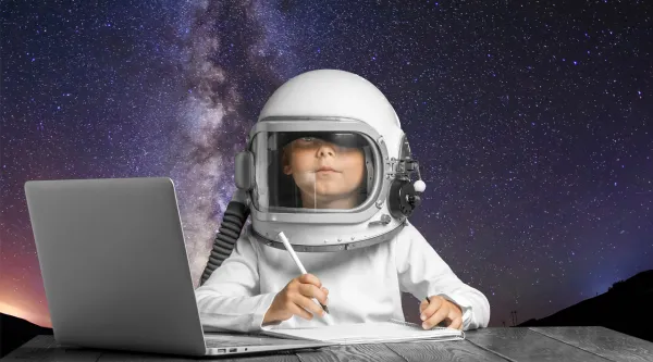 Ein Junge im Astronautenanzug sitzt vor einem Laptop