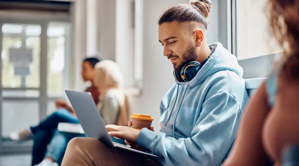 Student hat sein Laptop auf seinen Knien und arbeitet